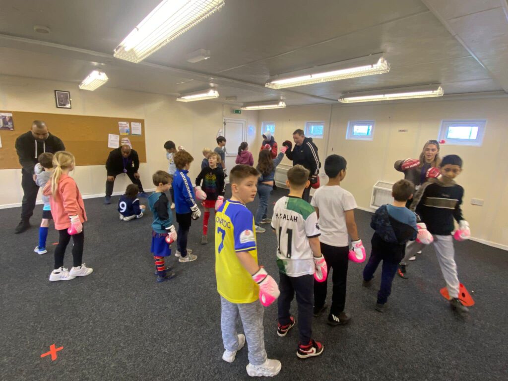 Children lined up wearing boxing gloves.