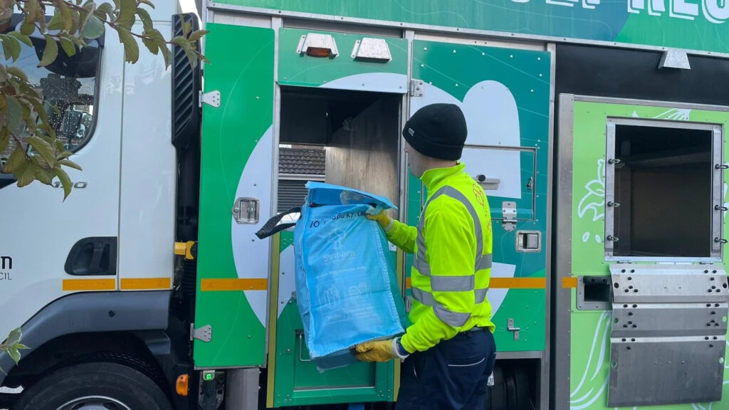 Worker recycling bag into lorry.