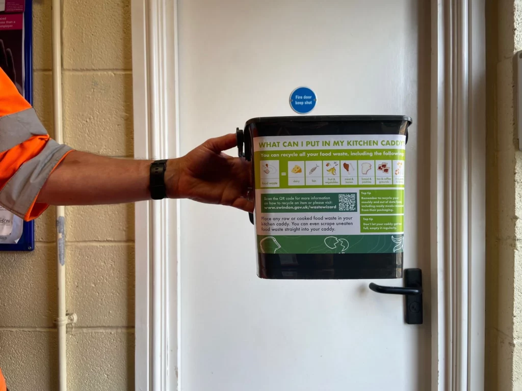 hand holding out a recycling caddy